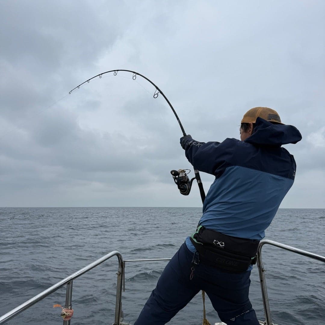 船上で魚とやり取りする釣り人の後ろ姿